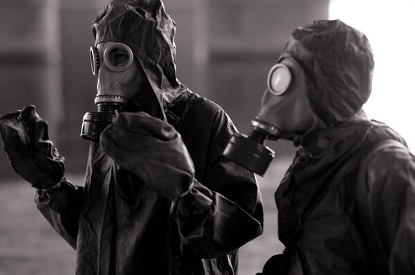 Two persons in NBC protective suits and gas masks. Concept of a preventive measures and protection for coronavirus COVID 19 pandemic and other global dangers.