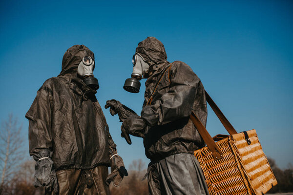 Couple in love walks in NBC protective suits and gas masks. Concept of a preventive measures and protection for coronavirus COVID 19 pandemic and other global dangers.