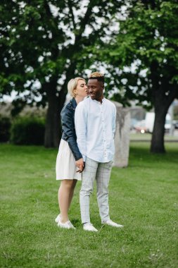 Irklar arası çift parkta el ele tutuşup öpüşüyor. Farklı insan ırkları arasındaki aşk ilişkileri ve birlik kavramı.