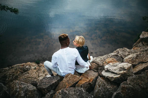 Міжрасові Пари Сидять Скелях Обіймаються Тлі Річки Концепція Любовних Відносин — стокове фото