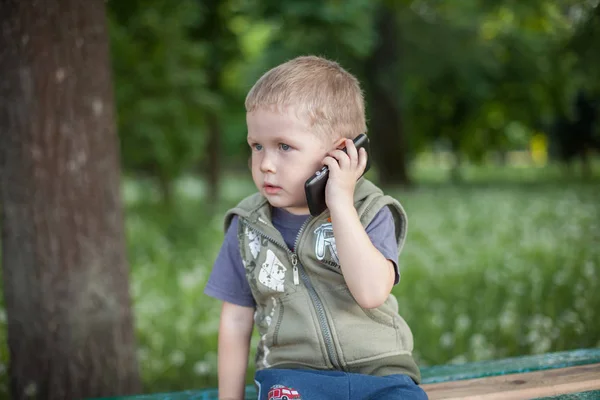 Malý chlapec mluvil po telefonu při posezení venku — Stock fotografie