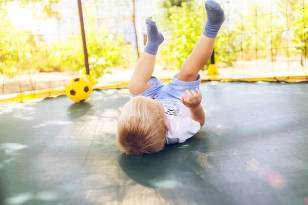 Jongen spelen met een bal, springen op een trampoline Rechtenvrije Stockafbeeldingen