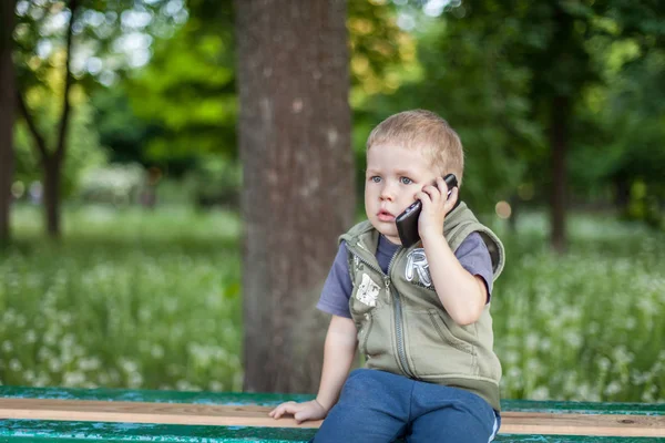 Malý chlapec mluvil po telefonu při posezení venku — Stock fotografie