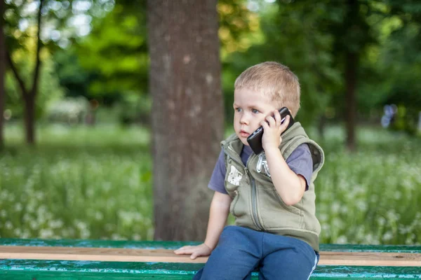 Malý chlapec mluvil po telefonu při posezení venku — Stock fotografie