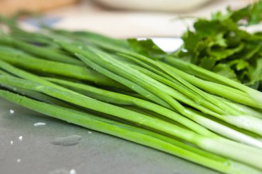 Mutfak masasının üzerinde taze yeşil soğan yakın çekim.