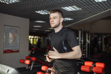 Bir adam, bir adam bir koşu bandı üzerinde spor salonunda çalışıyor,