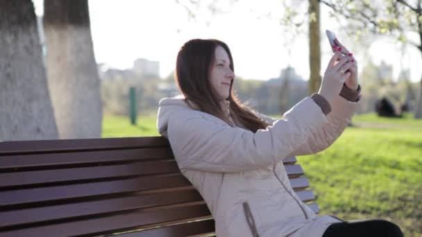 Meisje met telefoon zitten in het park — Stockvideo