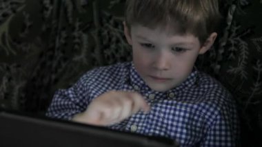 Çocuk tablet üzerinde oynuyor. Karanlıkta.
