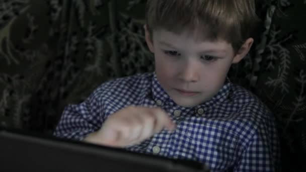 Chlapec si hraje na tabletu. Ve tmě. — Stock video