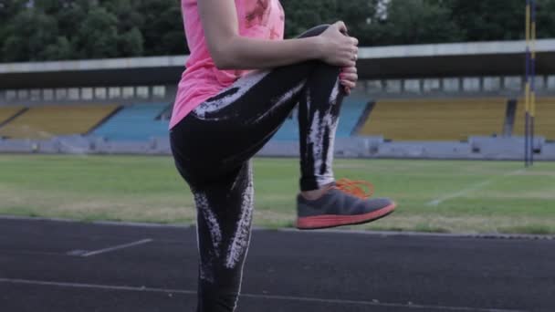 Dehntraining für Frauen. Fitness-Frau streckt Beine vor dem Training auf der grünen Wiese. junges Mädchen, das die Beine streckt. Aufwärmen vor dem Training. junge Frau macht Dehnübungen — Stockvideo