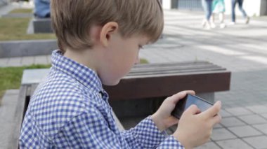 Genç çocuk smartphone şehir içinde oynamaya. Cep telefonu olan çocuk. Küçük çocuk sokakta smartphone ile oynamak