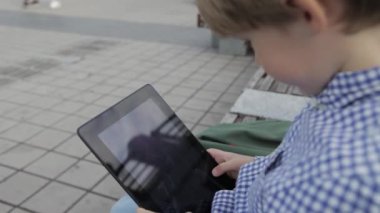 Çocuk tablet üzerinde oynuyor. Onun elinde bir elektronik tablet ile küçük bir çocuk.
