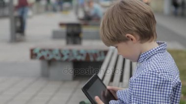 Çocuk tablet üzerinde oynuyor. Onun elinde bir elektronik tablet ile küçük bir çocuk.