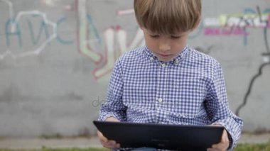 Çocuk tablet üzerinde oynuyor. Onun elinde bir elektronik tablet ile küçük bir çocuk.