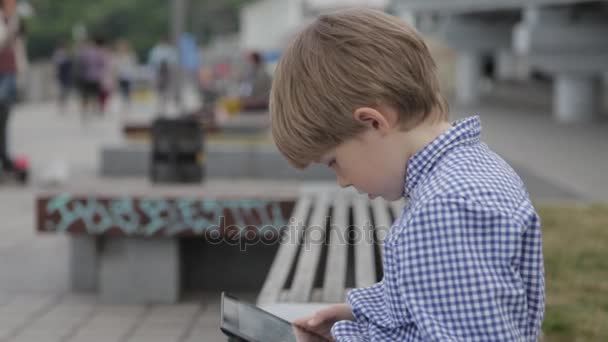 少年は、タブレットで遊んでいます。彼の手で電子タブレットを持った少年. — ストック動画