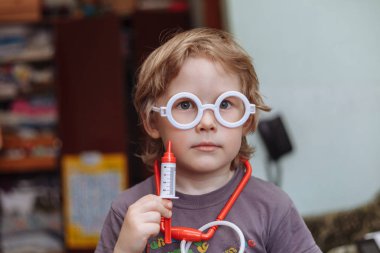 Küçük bir çocuk doktoru oynuyor. Küçük beyaz çocuk doktor. A atış, elinde bir şırınga.