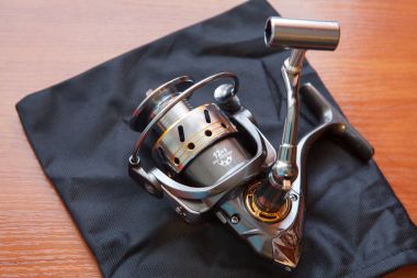 Reel balıkçılık çubuklar için ahşap arka plan üzerine kapatalım. Balık tutma bobin yakın çekim.