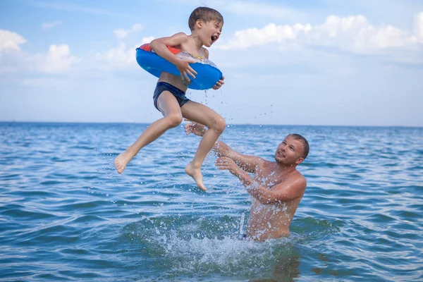 Baba ve oğlu denizde banyo, eğlenceli oyun. Baba oğlunu suya atar..