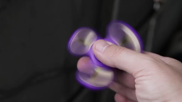 Spiel mit dem lila Fidget Spinner. Spielzeugschleuder in der Hand. — Stockvideo