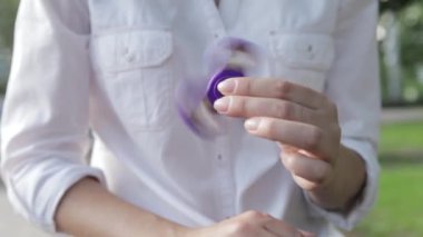Onun elinde dönen bir iplik oyuncakla oynayan bir kız. Kız twirks açık havada spinner