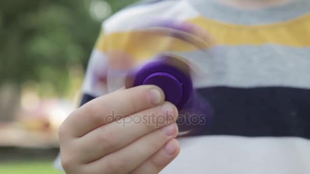 A little boy is playing with a spinner. The boy is spinning a spinner in his hand. — Stock Video