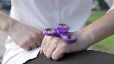 Onun elinde dönen bir iplik oyuncakla oynayan bir kız. Kız twirks açık havada spinner.