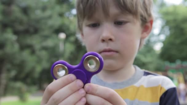 Malý chlapec hraje s spinner. Chlapec se točí číselník v ruce. — Stock video