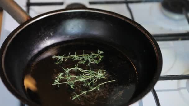 El tomillo se coloca en una sartén con aceite de girasol. Las ramitas de tomillo fresco se colocan en una sartén en aceite de oliva . — Vídeos de Stock