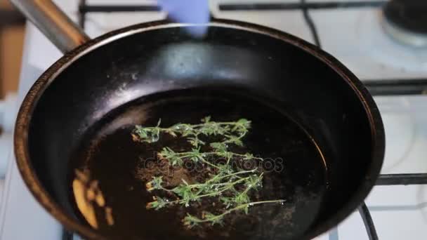 Las ramitas de tomillo fresco se tuestan en aceite de oliva en una sartén . — Vídeos de Stock