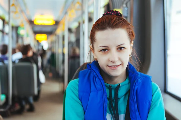 一个女孩在城市交通方面，在一辆电车的画像。漂亮的年轻女人对路面电车缆车，期间她上班学校. 图库照片