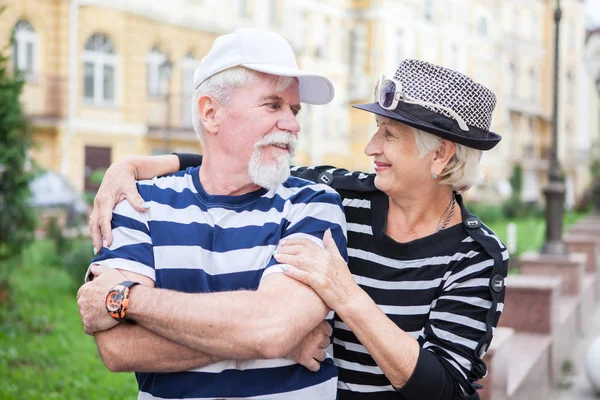 Liefdevolle bejaarde echtpaar poseren op camera. Gepensioneerden omhelzen elkaar. Gelukkige oude mensen. Stockafbeelding
