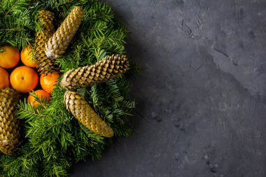 Noel köknar çelenk koniler ve beton zemin üzerine mandalina ile. Bir hanımefendi ile Üstten Görünüm