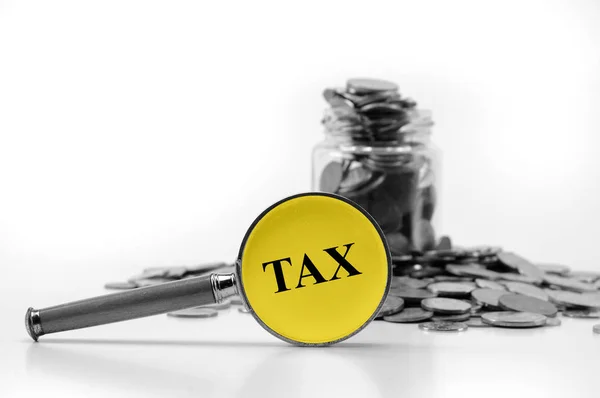 Tax concept with coins and magnifying glass — Stock Photo, Image