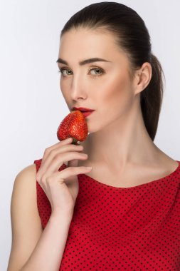 Elbiseli güzel kız. Öğe, dikey, mükemmel çıplak makyaj. Kameraya bakıyor. Kırmızı çilek yiyin. Sağlıklı gıda. Beyaz izole.