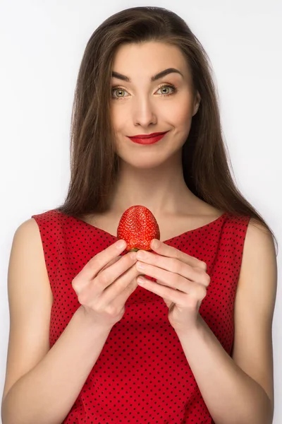 Hermosa chica en un vestido con una sonrisa perfecta comiendo fresa roja. Comida saludable. Aislado sobre blanco . — Foto de Stock