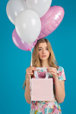 Baloons ile tatlı güzel kız ve küçük prersents çanta mavi zemin üzerine elinde. Bahar ruh hali