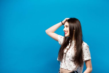 Genç kadın portre izole mavi duvar arka plan üzerinde düşünme. Beyaz gömlek.