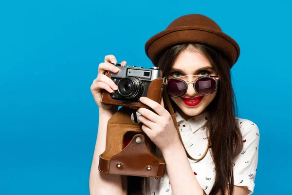 Belle fille en chapeau brun et lunettes de soleil rondes tenant la vieille caméra — Photo