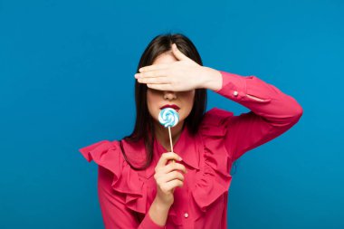 Güzel bir kadın ile bir lolipop, yüksek kaliteli güzellik mavi zemin üzerine kadar yakın