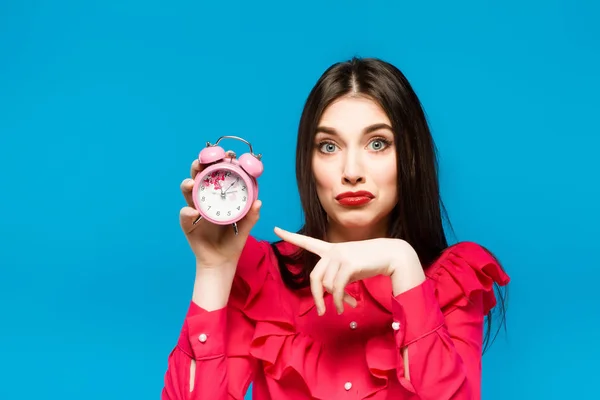 Mujer joven sosteniendo un reloj sobre un fondo azul —  Fotos de Stock