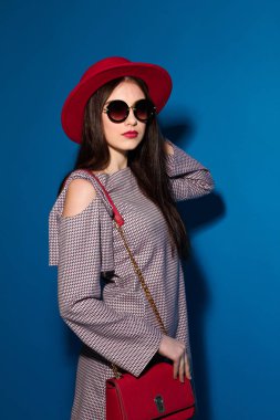 Güzel modeli şık kırmızı şapka ve mavi arka plan üzerinde kırmızı bir debriyaj