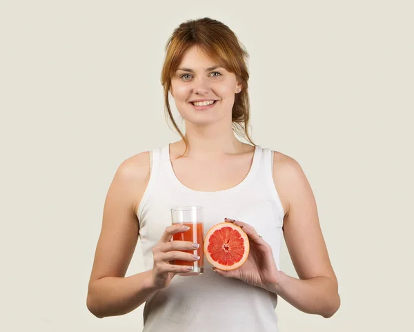Mujer deportiva sobre fondo gris sosteniendo vaso de zumo de pomelo — Foto de Stock