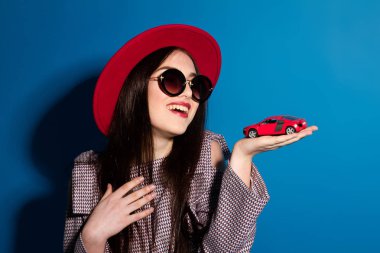 Güzel modeli şık kırmızı şapka ve araba mavi arka plan ile kırmızı bir debriyaj