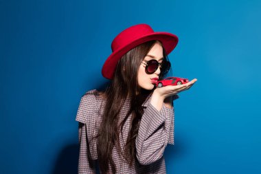 Güzel modeli şık kırmızı şapka ve araba mavi arka plan ile kırmızı bir debriyaj