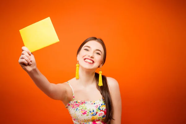 Hermosa mujer sonriente con sobre de correo. Sobre fondo naranja —  Fotos de Stock