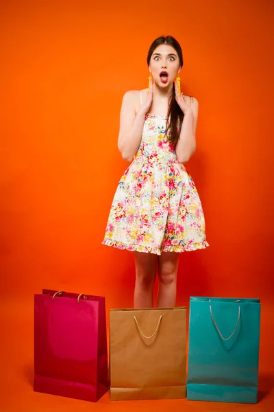 Ritratto di giovane donna con borse della spesa. sfondo arancione — Foto Stock
