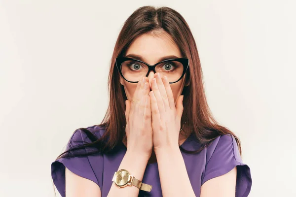 Joven hermosa mujer con expresión facial de sorpresa de pie sobre fondo gris. Llevar en vestido de moda y gafas. Mirando a la cámara — Foto de Stock