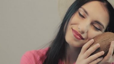 Genç kız gülümser ve Hindistan cevizi kokteyl içme bir mayo ve yaz şapkalı. gri arka planı