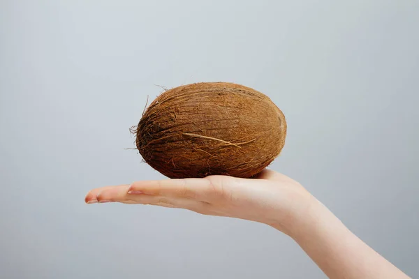 灰色の背景の手でナット ココナッツを持つ女性 — ストック写真
