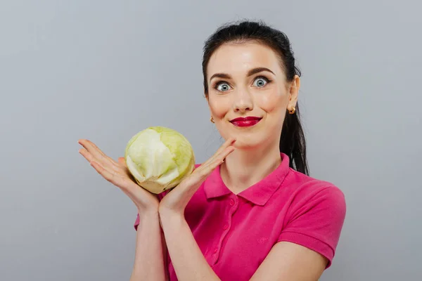 Raw food, veggie concept. Portrait of smiling good looking girl in casual clothing holding red cabbage in her hands over gray background. Healthy skin, glossy brown hair. Closeup. Studio shot. — Stock Photo, Image